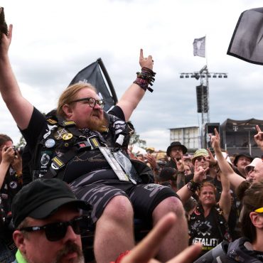 Ein Mann in einem Rollstuhl wird beim Crowdsurfen durch die Menge getragen.