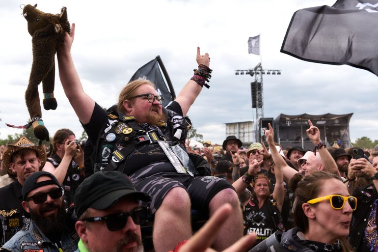 Ein Mann in einem Rollstuhl wird beim Crowdsurfen durch die Menge getragen.