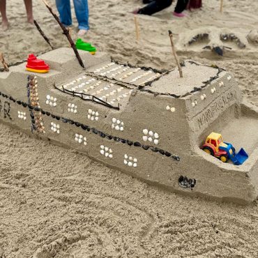 Kinder und Familien bauen beim Sandburgenwettbewerb auf Föhr kreative Sandskulpturen am Strand.