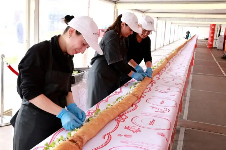 Helfer belegen das längste Fischbrötchen der Welt mit Matjes.