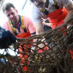 Freiwillige suchen an Deck die geborgenen Netze nach Meereslebewesen ab.