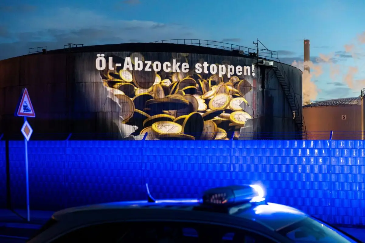 Auf einem Tank einer Raffinerie im Hamburger Hafen wird am frühen Morgen Geldregen projiziert.