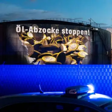 Auf einem Tank einer Raffinerie im Hamburger Hafen wird am frühen Morgen Geldregen projiziert.