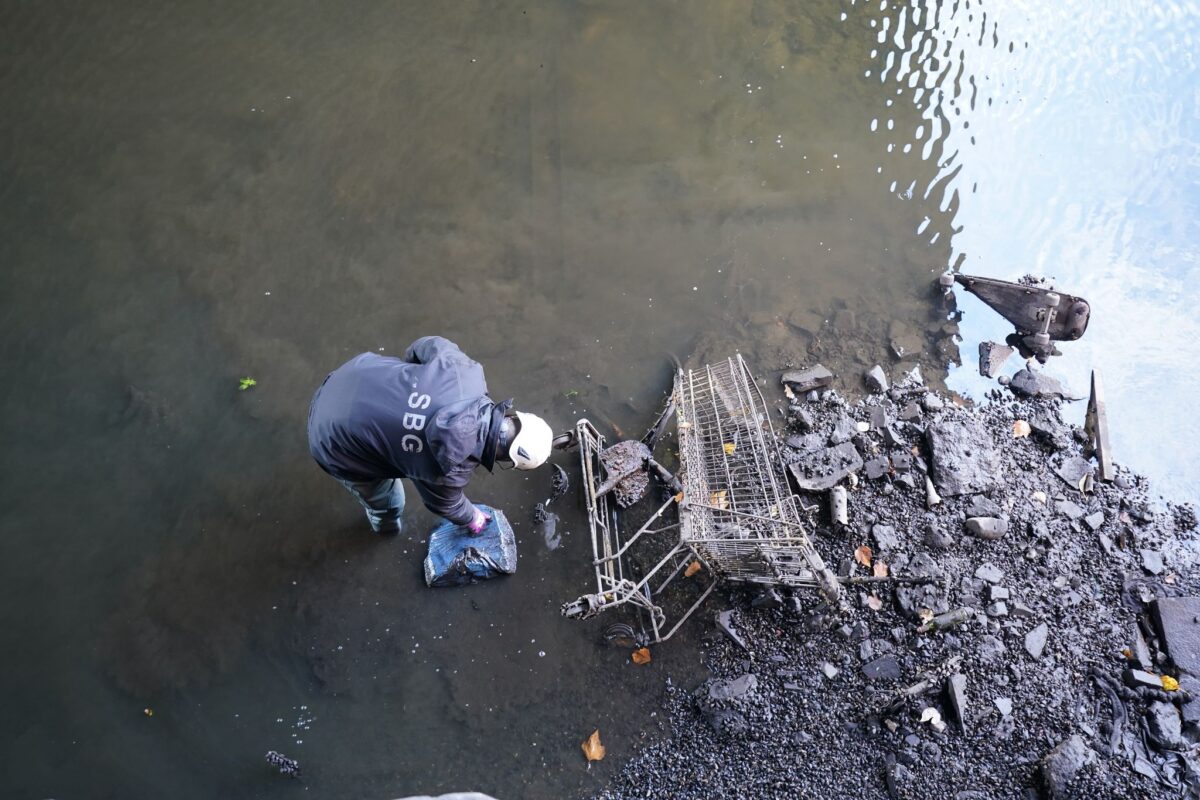 Ein Mitarbeiter des Landesbetriebs Straßen, Brücken und Gewässer reinigt den fast wasserleeren Alsterfleet. (Archivbild)