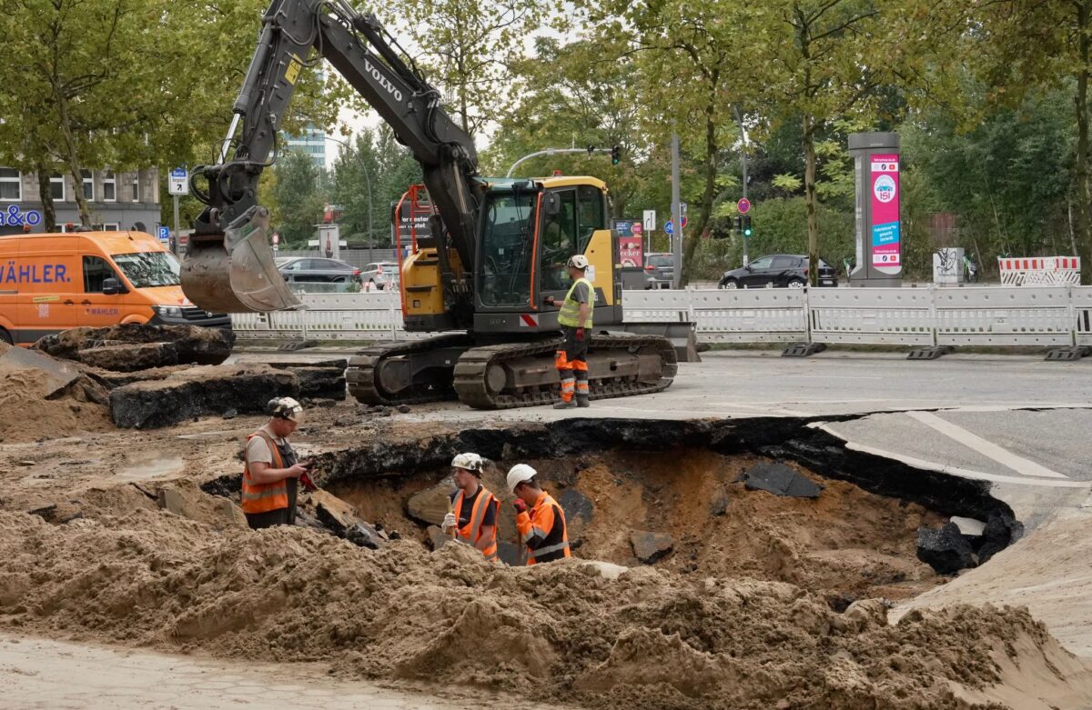 Nach einem Wasserrohrbruch in Hamburg in der Amsinckstraße arbeiten Bauarbeiter in einem Loch.