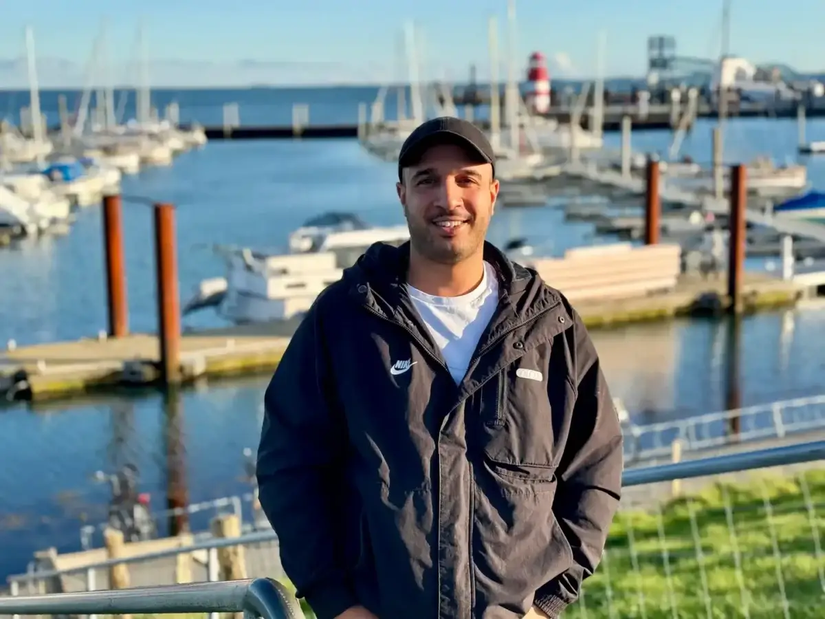Roberto Caso am Wyker Binnenhafen auf Föhr mit Segelbooten und Hafenanlagen im Hintergrund.