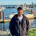 Roberto Caso am Wyker Binnenhafen auf Föhr mit Segelbooten und Hafenanlagen im Hintergrund.